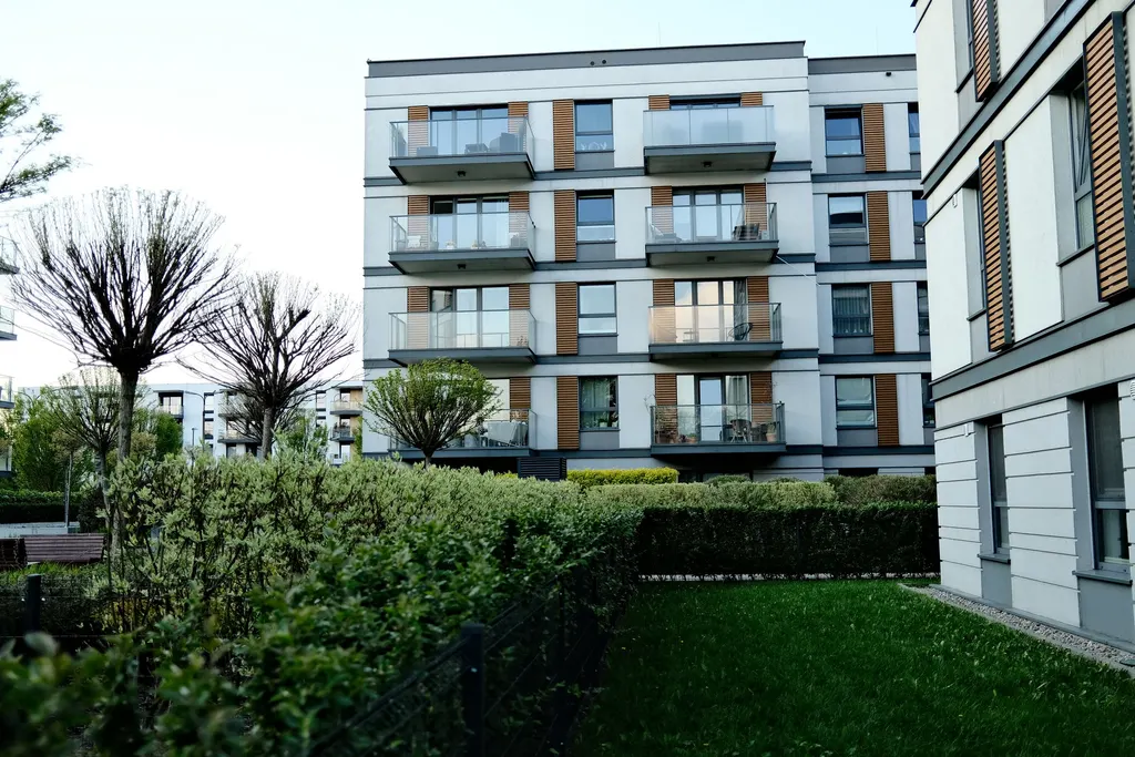 Gepflegte Grünanlage mit Hecke und Rasen vor einem Wohngebäude