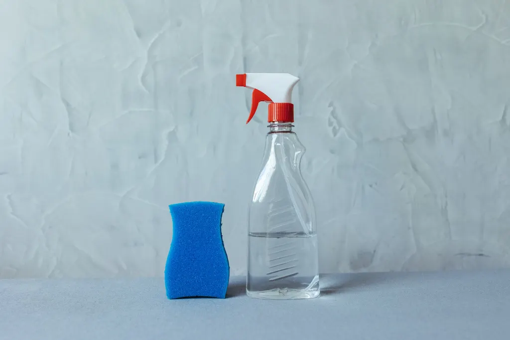 Sprühflasche und Schwamm auf grauem Grund